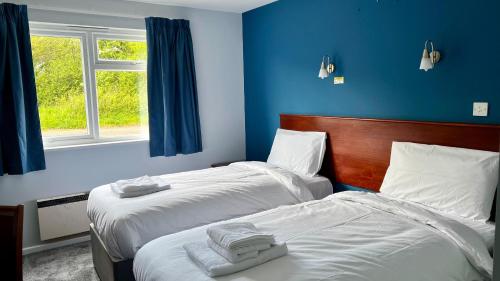 米尔顿凯恩斯MK Hotel的蓝色墙壁客房的两张床