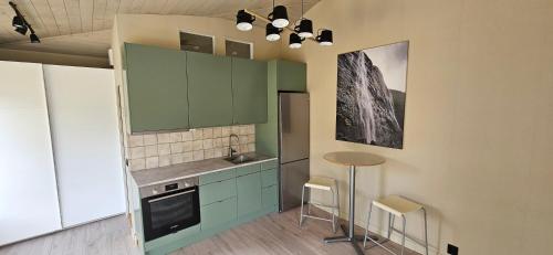 胡迪克斯瓦尔Lägenhet Ateljén的厨房配有绿色橱柜和桌椅