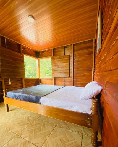 图里亚尔瓦Cabaña Monarca的木制客房内的一间卧室,配有一张床