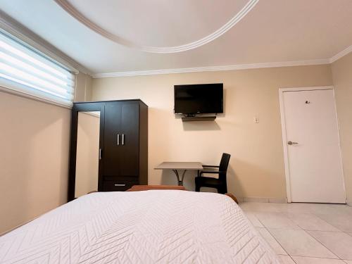 瓜亚基尔Suitesecu Guayaquil的一间卧室配有一张床、一张桌子和一台电视。