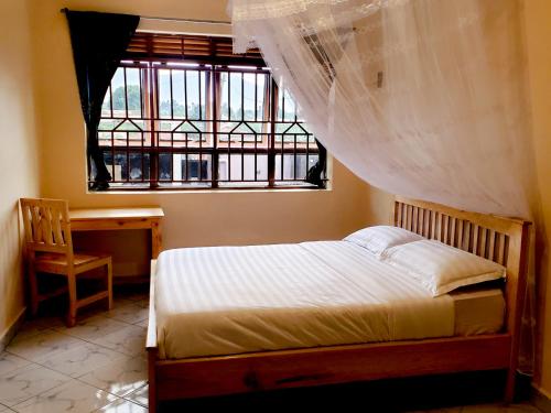 KisoroMianzi Guest House的一间卧室配有一张床、一张书桌和一个窗户。