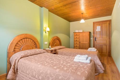 帕拉莫Apartamentos Blanca Senda del Oso的一间卧室设有两张床和木制天花板