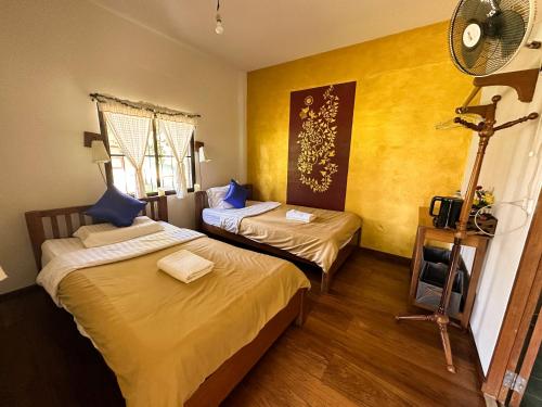 拜县Pairadise Hotel的黄色墙壁客房的两张床