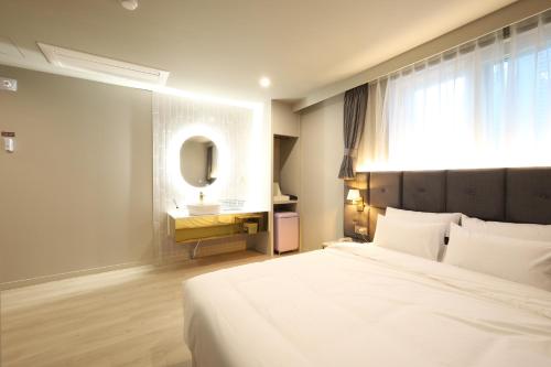 昌原市Changwon Denbasta Hotel Myeongseo的一间卧室配有床、水槽和镜子