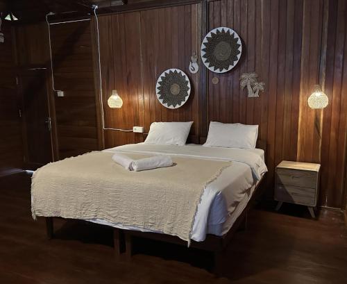 TapokrengVogelkopf Resort的一间卧室配有一张带木墙的大床