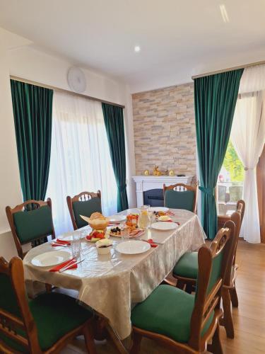 瓦杜伊泽Pensiunea Casa Ancuta的一间带桌子和绿色椅子的用餐室