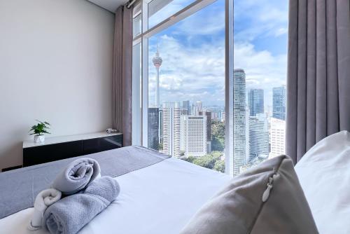 吉隆坡吉隆坡会展中心勒雅拉套房公寓的一间卧室设有大窗户,床上配有毛巾
