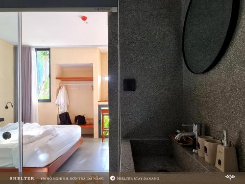岘港Shelter Stay Da Nang的一间带一张床的卧室和一间带镜子的浴室