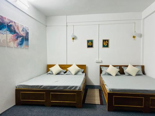 MirikMirik Homestay的白色墙壁客房的两张床