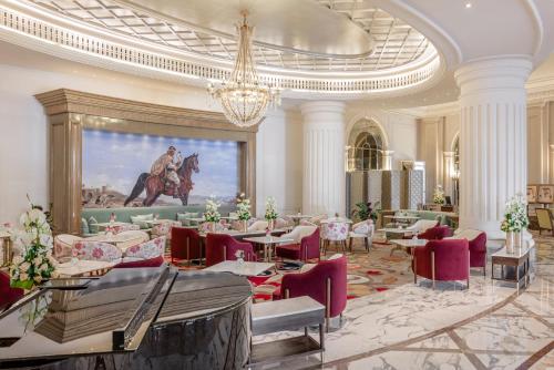 迪拜Al Habtoor Palace的一间带桌椅的用餐室和一幅画