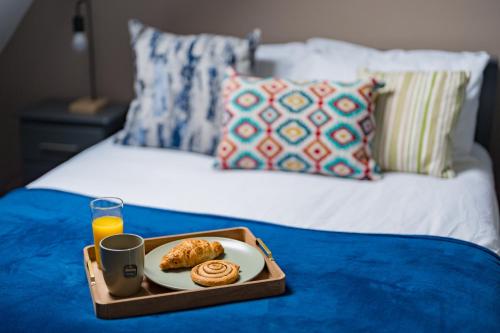 SheldonStylish apartment near NEC, Birmingham Airport, Resorts World, HS2, JLR的床上的食品托盘和一杯橙汁