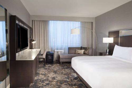 欧文Dallas/Fort Worth Airport Marriott的酒店客房配有一张床、一把椅子和一台电视。