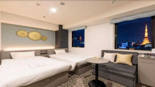 东京Henn na Hotel Tokyo Hamamatsucho的酒店客房设有两张床、一张桌子和一个窗户。