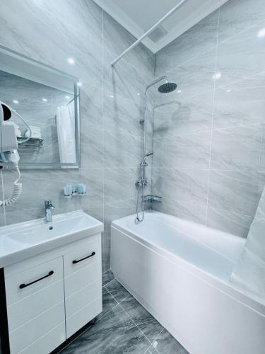 卡拉甘达Hotel Bereket Karaganda的白色的浴室设有浴缸和水槽。