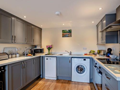 查姆利2 bed property in Chulmleigh Devon 75273的厨房配有灰色橱柜、洗衣机和烘干机