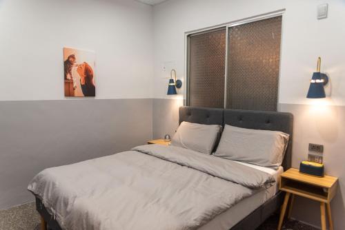 龙井圈圈宿QQs & 三點不陋SDBL的一间卧室配有一张带白色床单的床和一扇窗户。