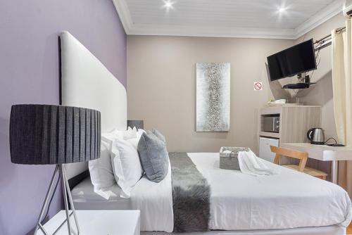 弗里尼欣Botle Ba Afrika Lodge的一间卧室配有一张床、一张桌子和一台电视