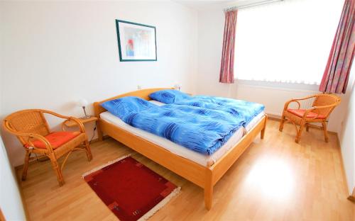 格尔斯费尔德Gästehaus Jäger Ferienwohnungen的一间卧室配有一张带蓝色床单的床和两把椅子