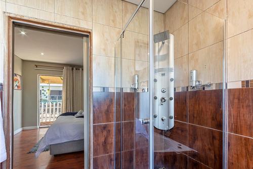 弗里尼欣Botle Ba Afrika Lodge的一间带玻璃淋浴的浴室和一张床