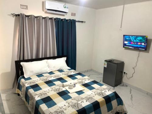 卢萨卡Radiant lodge的卧室配有一张床,墙上配有电视。