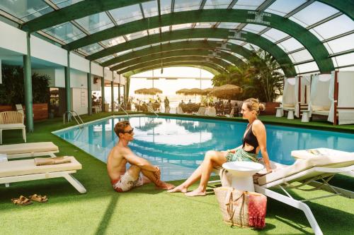 阿雷西费阿瑞斯弗格兰酒店及水疗中心的坐在游泳池旁的男人和女人