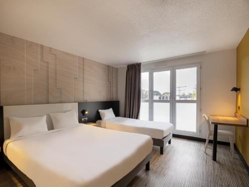 普洛埃默B&B HOTEL Lorient Ploemeur的酒店客房设有两张床和窗户。