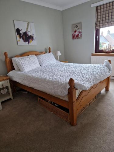 普雷斯蒂克Troon Open golf - Private house with garden in central Prestwick的一间卧室配有一张大木床和白色床单