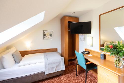 不莱梅Hotel Garden Bremen的酒店客房配有一张床、一张书桌和一台电视。