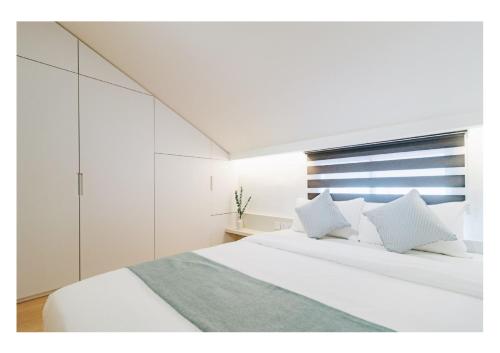 新加坡Serenity Suite的卧室配有白色的白色床和白色的橱柜。