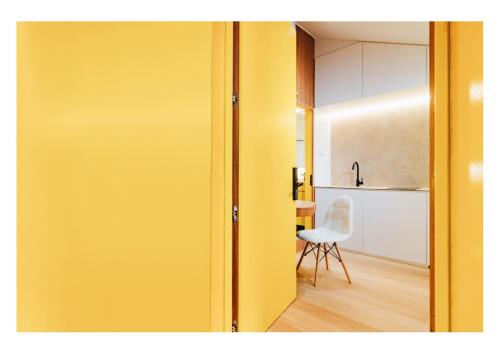 新加坡Serenity Suite的黄色的门通向带椅子的厨房