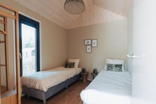 伊皮Knus I Tiny house op de Veluwe的一间卧室设有两张床和窗户。