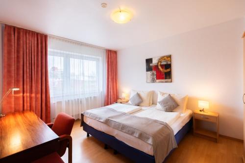 不莱梅Novum Hotel Garden Bremen - Apartments的一间卧室配有一张床、一张书桌和一个窗户。