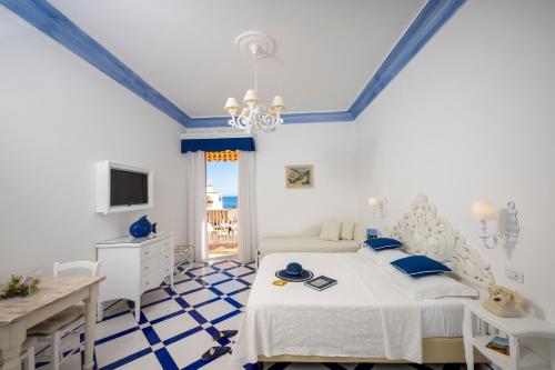 波西塔诺弗拉维奥焦亚别墅酒店的一间卧室配有一张床、一张书桌和一台电视