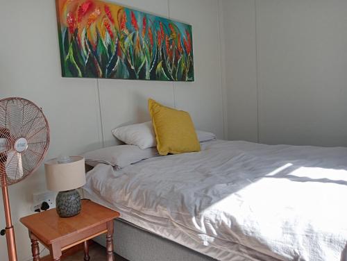 塔尔巴赫Winterhoek Farm Cottage的一间卧室配有一张带黄色枕头的床和风扇