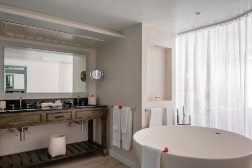 格罗斯岛BodyHoliday St Lucia的白色的浴室设有大浴缸和镜子
