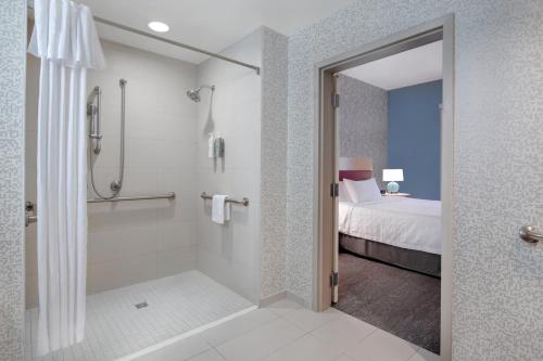 塔斯卡卢萨Home2 Suites by Hilton Tuscaloosa Downtown University Boulevard的带淋浴、床和淋浴的浴室位于后门。