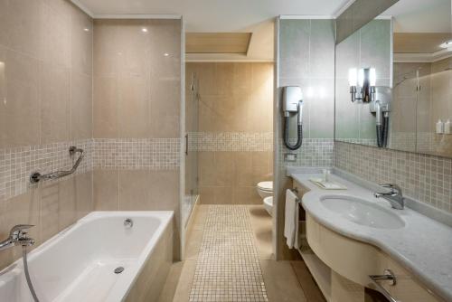 佩罗UNAHOTELS Expo Fiera Milano的一间带两个盥洗盆、浴缸和卫生间的浴室