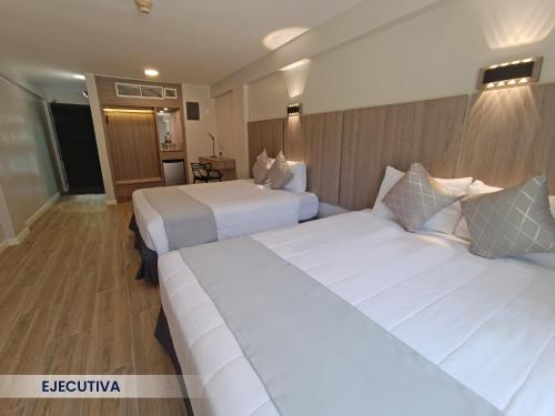 波拉马尔Hotel Margarita Dynasty的配有白色床单的酒店客房内的两张床