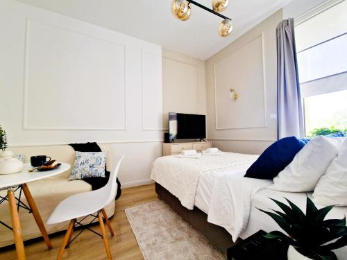 华沙J&W Apartments Grójecka Glam Flat的一间卧室配有一张床、一张桌子和一台电视。
