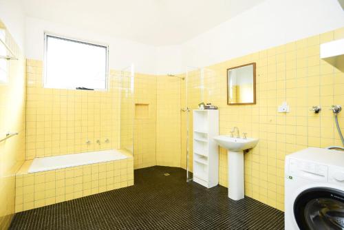 Goolwa NorthPelican Cottage - Pet Friendly - Wifi的黄色瓷砖浴室设有水槽和洗衣机