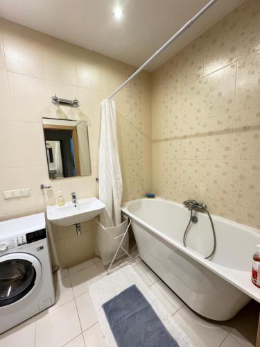 里加Vaidava’s Apartment的带浴缸和洗衣机的浴室。