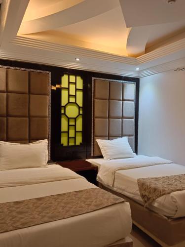 吉赞Aldar Hotel的一间卧室设有两张床和彩色玻璃窗。