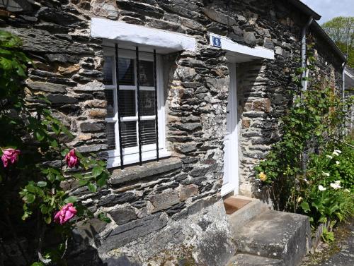 CaurelCaurel Cottage的一座石头房子,有窗户和一些鲜花