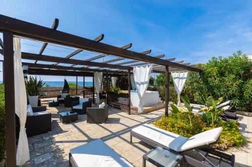 托雷圣乔万尼乌La Giara Resort的凉棚下带沙发和椅子的庭院