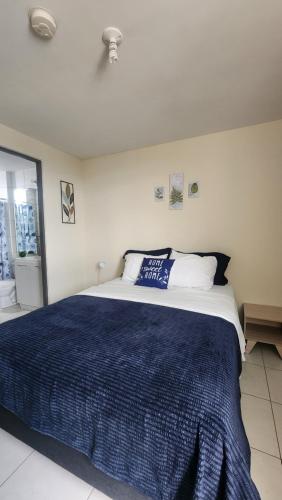 Ciudad RadialQuédate con sulay habitación a 5mint del aeropuerto的一间卧室配有一张带蓝色毯子的大床