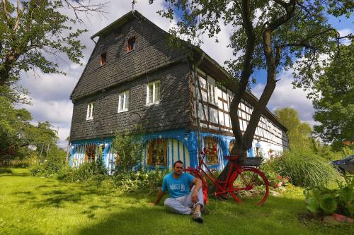 希维拉杜夫-兹德鲁伊Gesamtes Ferienhaus in Wolimierz mit Offenem Kamin的坐在房子前面的草上的人