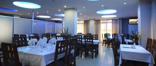 达卡随心假日酒店 的餐厅配有桌椅和白色的桌布