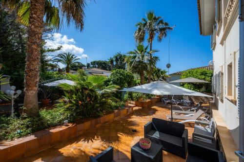 坎帕斯蒂利亚Villa Pedro strandnah ruhig zentral的一个带椅子和遮阳伞及棕榈树的庭院
