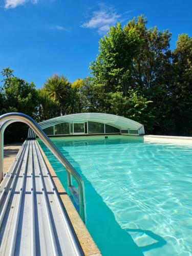 永河畔拉罗什Chambre d'hôte BALI的游泳池旁设有长凳
