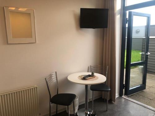 帕兹堡Motel eat´n drive Padborg的一间配有电视的房间里,一张白色的桌子和椅子